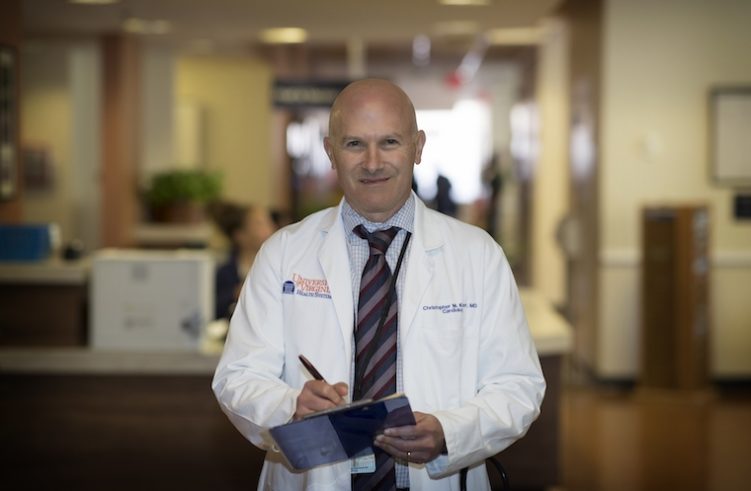 UVA's Christopher M. Kramer holds a clipboard and pen in a clinic.