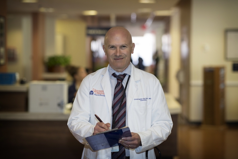 UVA's Christopher M. Kramer holds a clipboard and pen in a clinic.