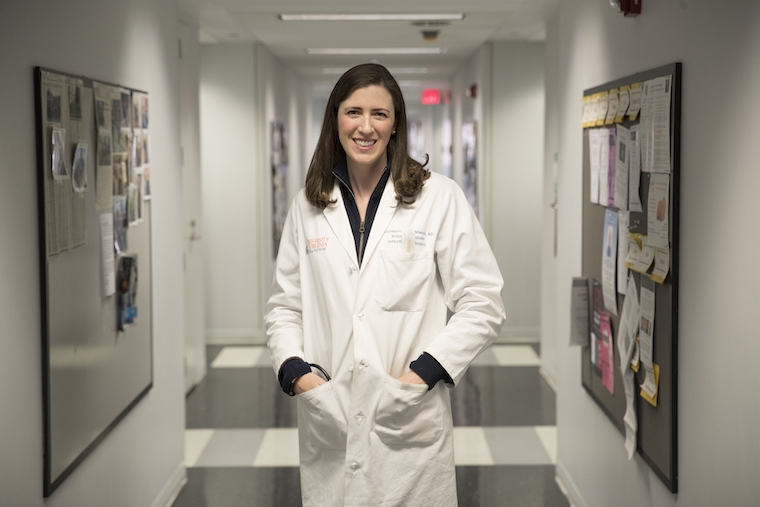 Researcher Kathleen A. McManus smiles in a hallway.