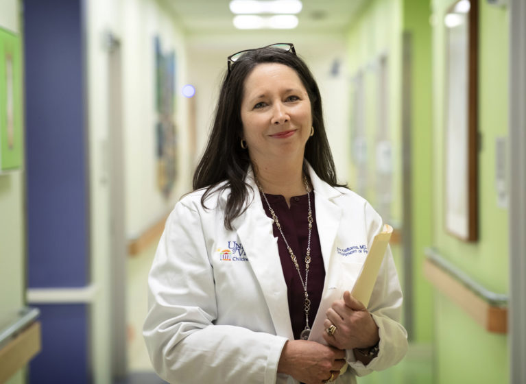 Ann Kellams holds a yellow folder in a hallway outside patient rooms.