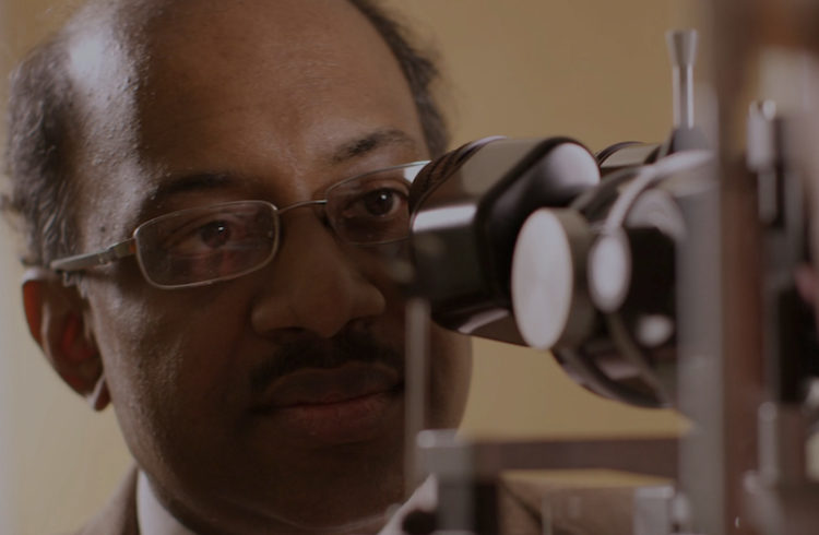 Jayakrishna Ambati peers into a microscope.