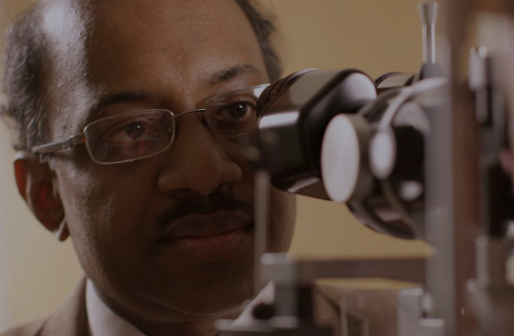 Jayakrishna Ambati peers into a microscope.