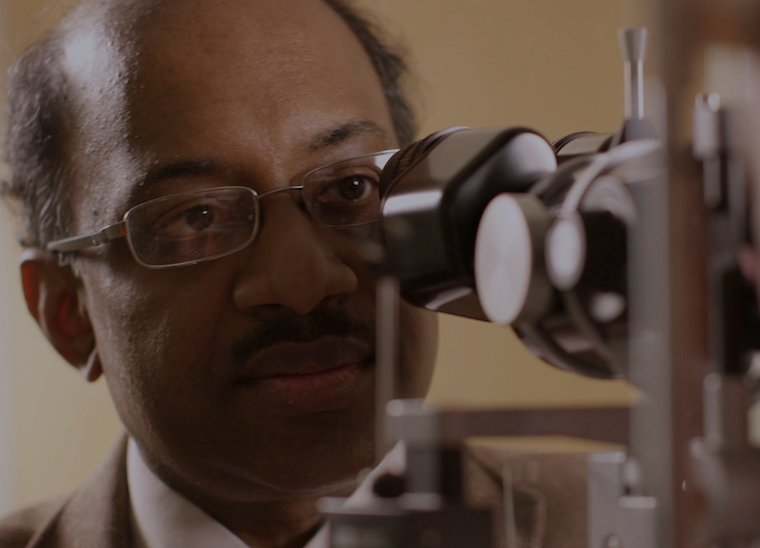 Jayakrishna Ambati peers into a microscope.