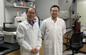 Hui-wang Ai and Shen Zhang stand in front of lab hood.
