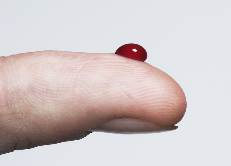 A finger with a drop of blood on it.