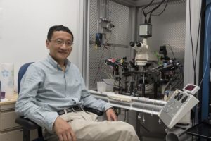 J. Julius Zhu poses with a microscope in his lab.