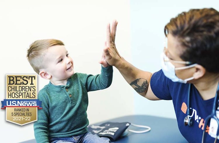 A toddler gives a high-five to a UVA Health team member. Text notes that UVA was ranked in 5 specialties for 2021-22 by U.S. News.