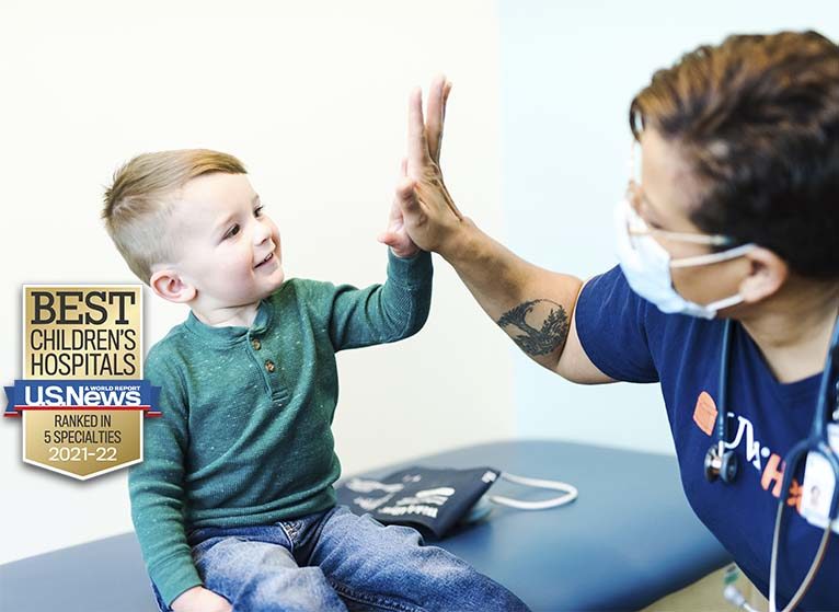 A toddler gives a high-five to a UVA Health team member. Text notes that UVA was ranked in 5 specialties for 2021-22 by U.S. News.