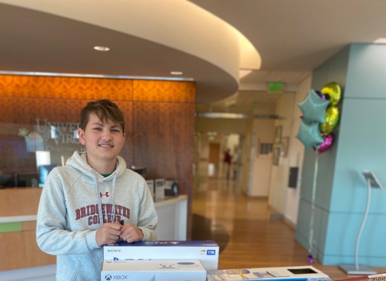 Luke Post poses with footballs and toys for children receiving treatment at UVA.