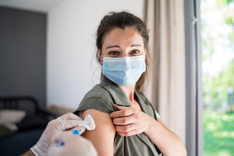 A masked woman receives a vaccination.