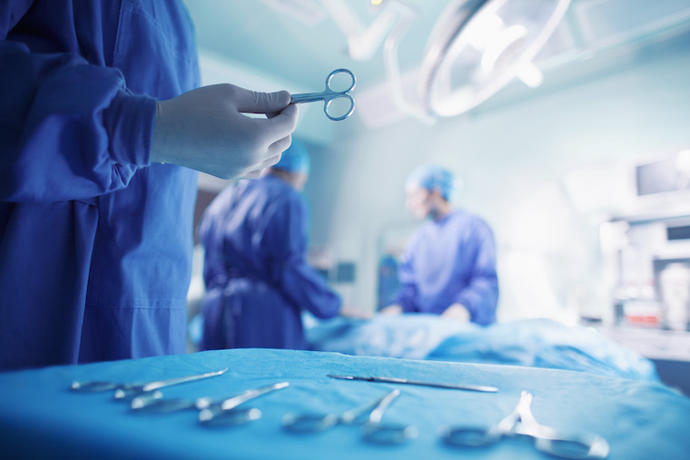 A surgeon clutches surgical shears in an operating room.