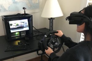 A person uses a driving simulator while wearing a virtual reality headset.
