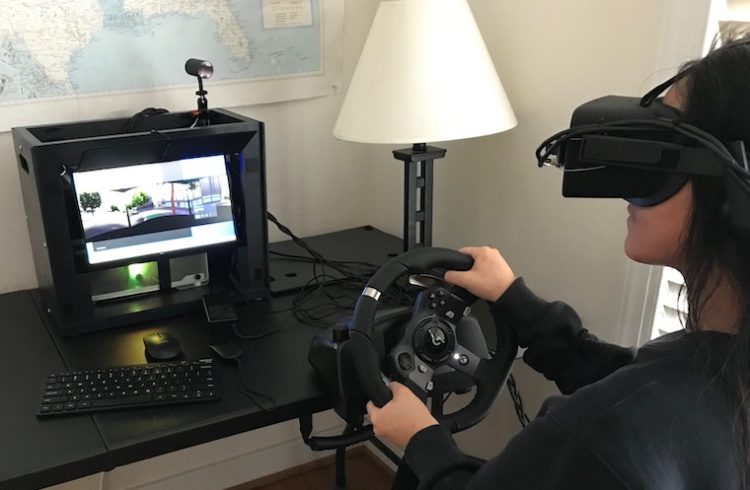 A person uses a driving simulator while wearing a virtual reality headset.