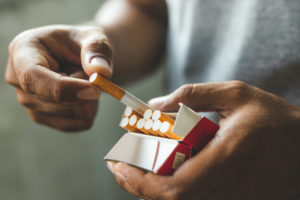 A man pulls a cigarette from a half-empty pack.