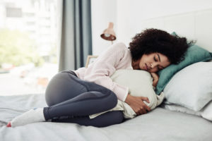 Woman curled in bed experiencing premenstrual symptoms.