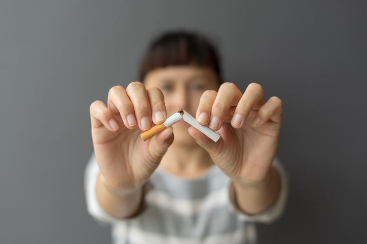 Portrait young woman holding broken cigarette in hands.