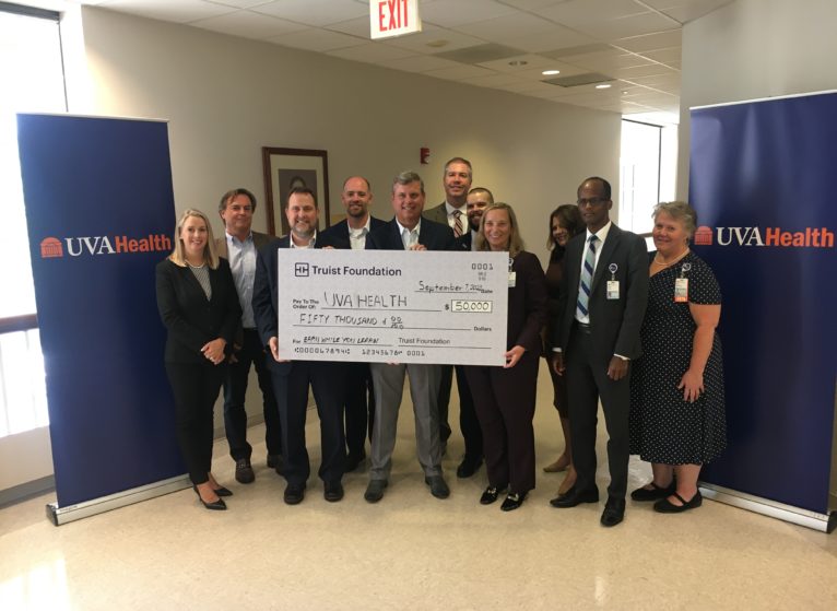 UVA Health and Truist representatives holding an oversized check.