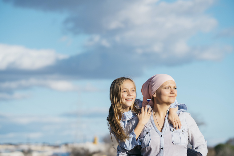 A woman with cancer is hugged by her daughter.