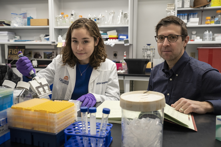 Researchers Kristine Zengeler and John Lukens work at a lab bench.